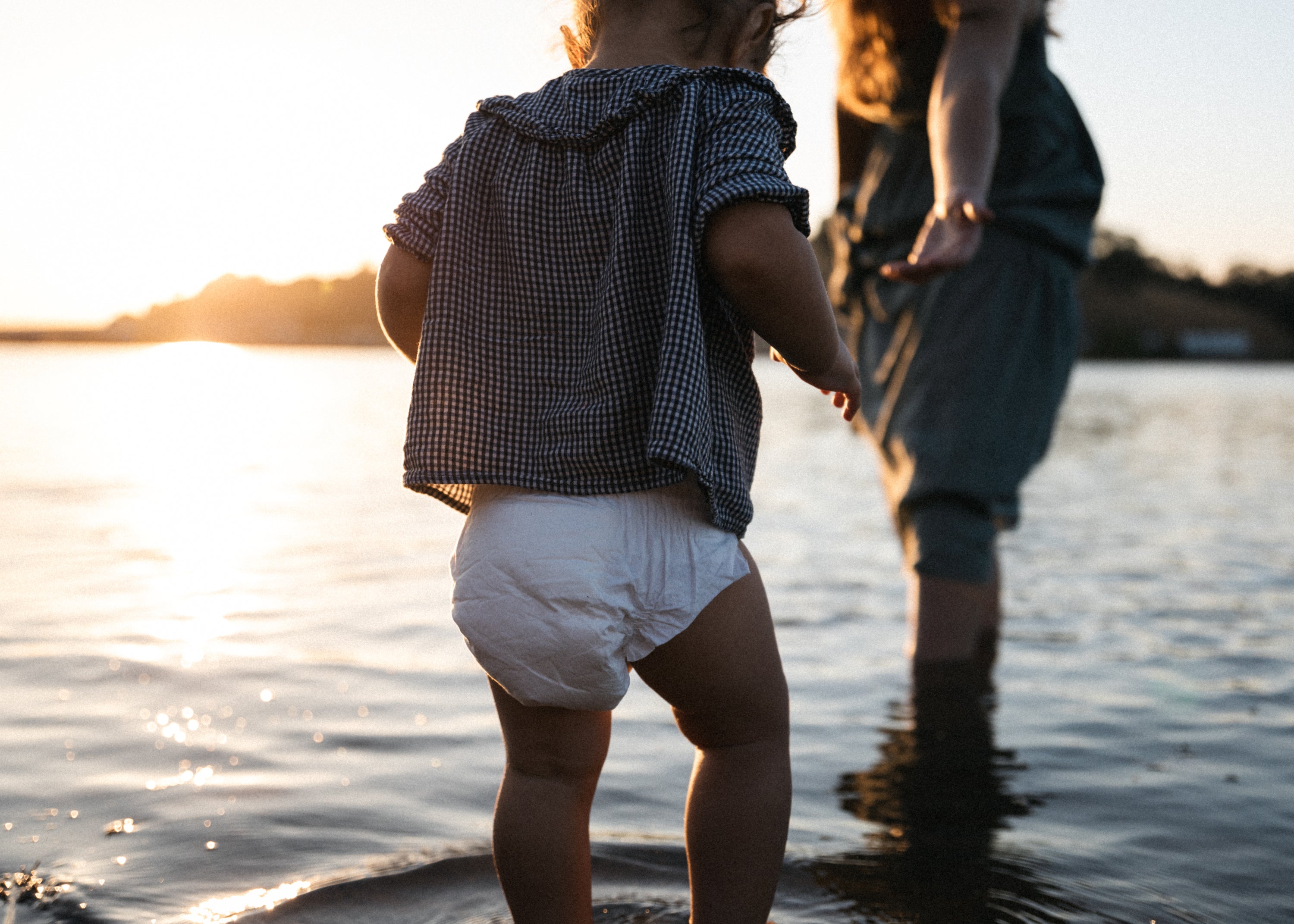 mother and baby holding hands sunset at beach